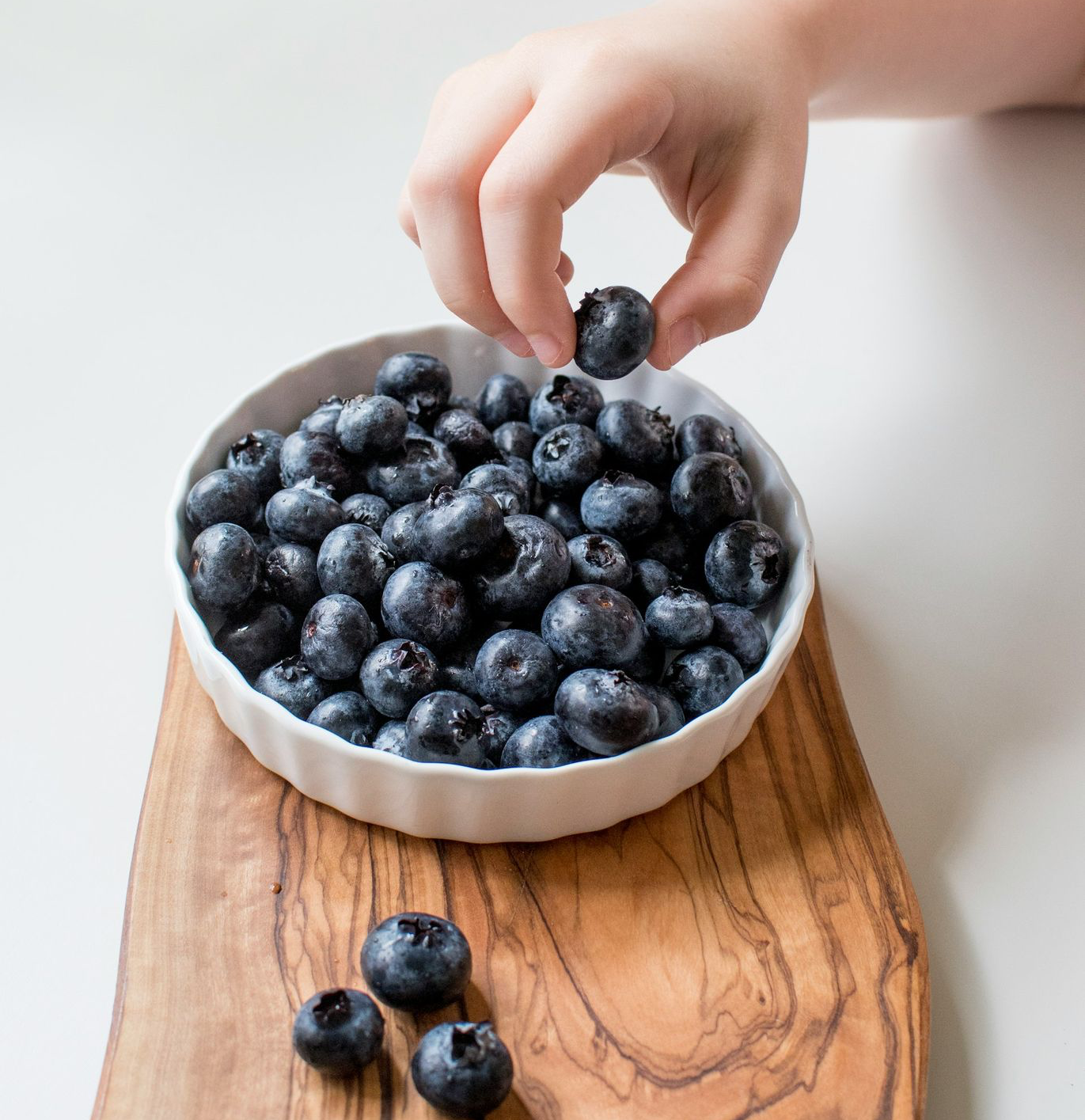 person holding bowl of black berries